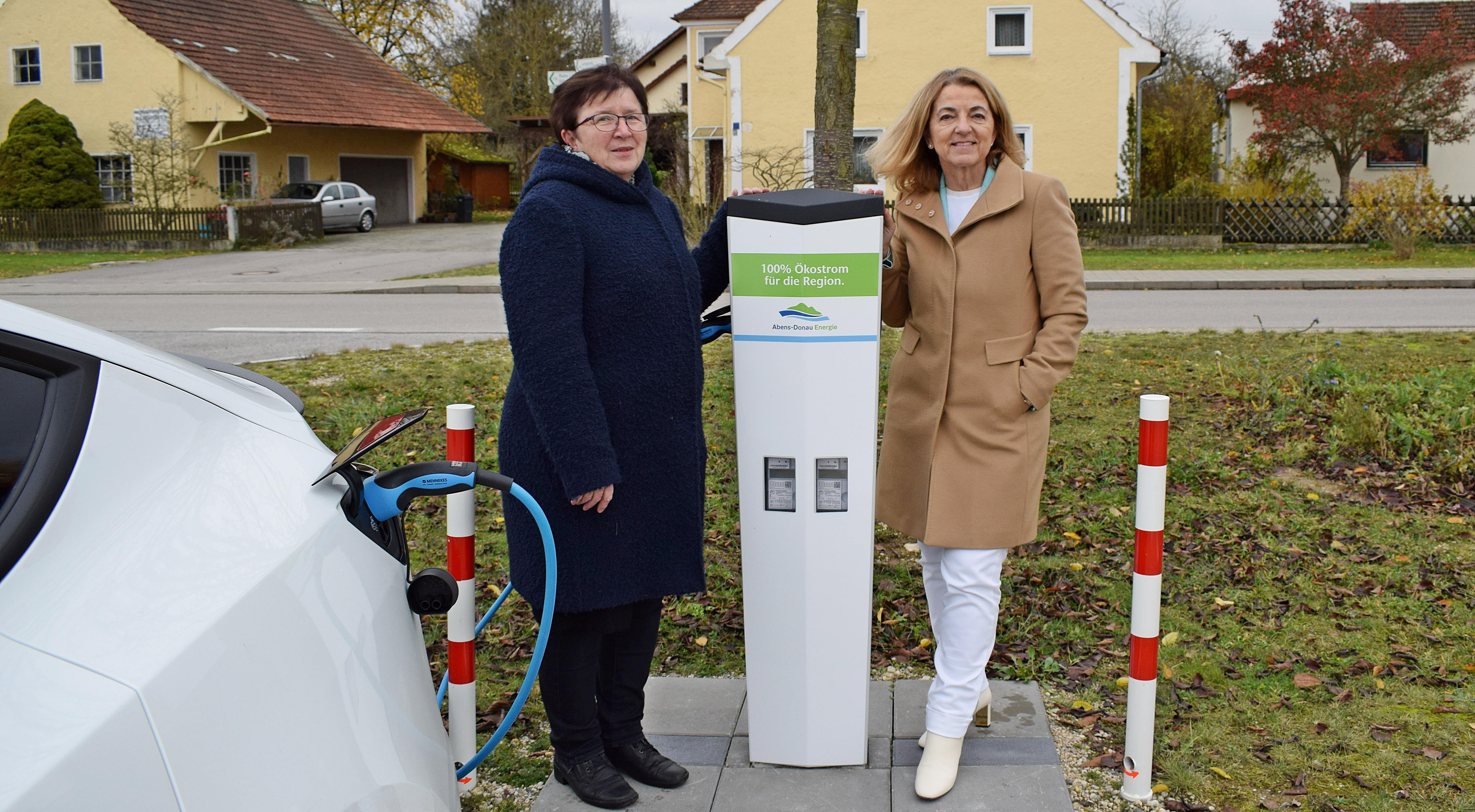 Zwei Frau stehen neben einer E-Ladesäule der Abens-Donau Energie, an der gerade ein Auto lädt.
