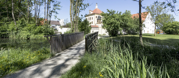 Bach mit Brücke und dem Wasserschloss Train im Hintergrund.