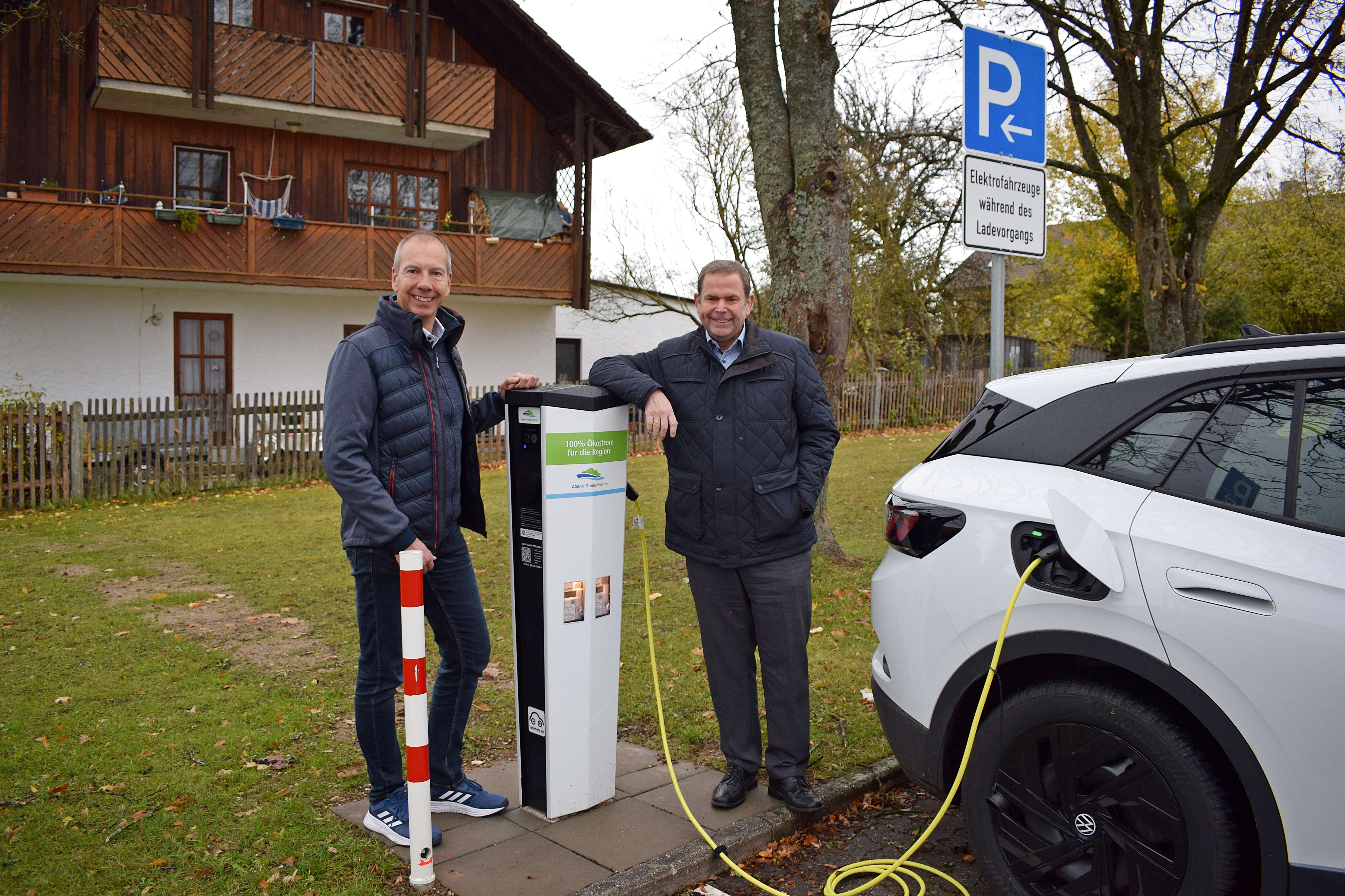 Zwei Männer laden ihr Auto an einer Ladesäule der Abens-Donau Energie in Ihrlerstein und weihen sie ein.