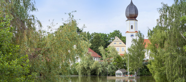 See mit Bäumen und der Pfarrkirche Mariä Himmelfahrt in Herrngiersdorf